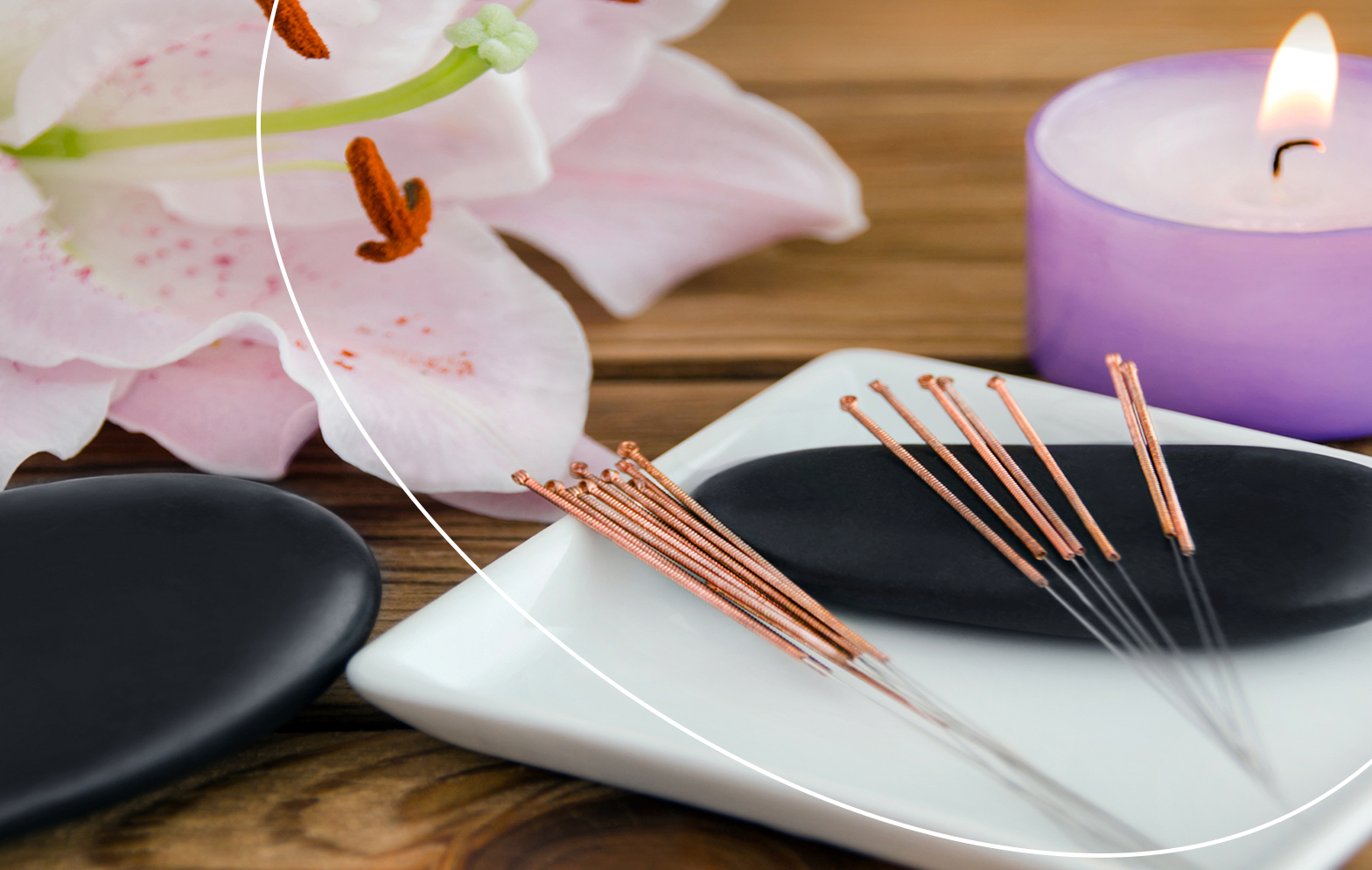 Sada akupunkturních jehliček položená na misce vedle svíčky a květu orchideje